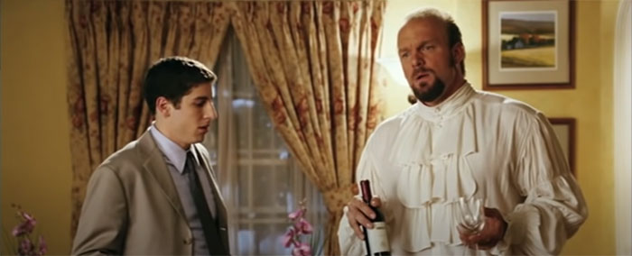 Scene from American Wedding movie featuring two men, one holding a wine bottle and glass, celebrating wedding movies.