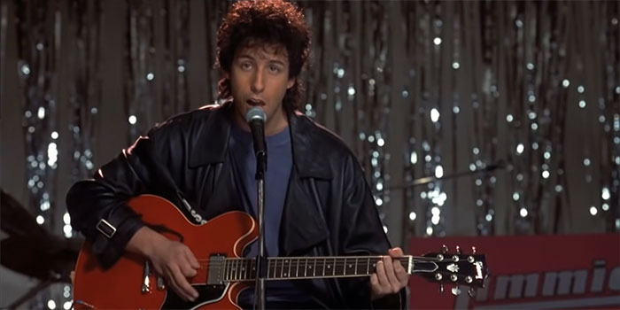 Scene from The Wedding Singer movie showing a man playing guitar and singing in one of the best wedding movies.