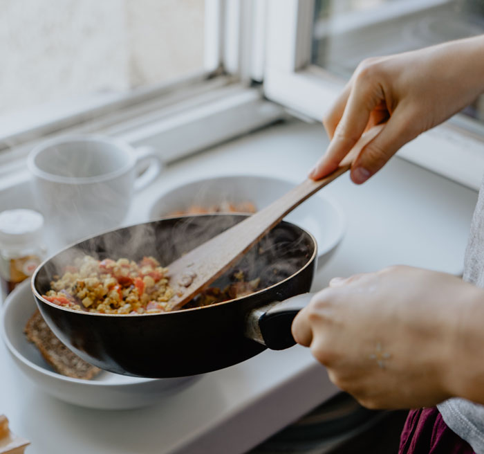 Person dividing food into plates from a pan 