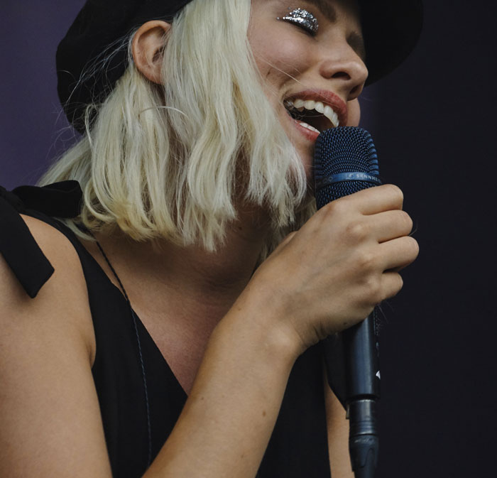 Blond haired woman singing into a microphone 