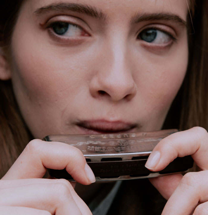 Woman blowing into a harmonica 
