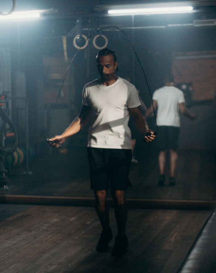 Man jumping over a rubber band in a gym 