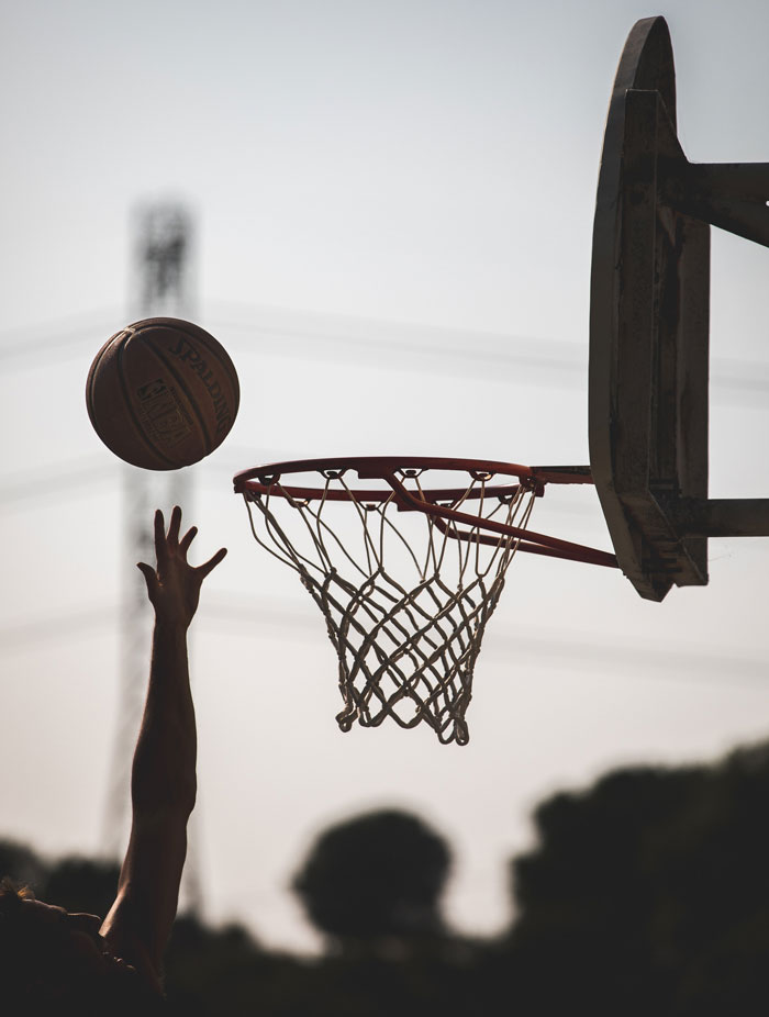 Man laying up a basketball ball into a basketball hoop 