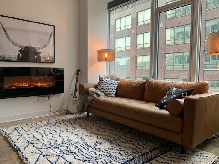 Cozy living room decoration with leather sofa, abstract rug, guitar, and modern art.