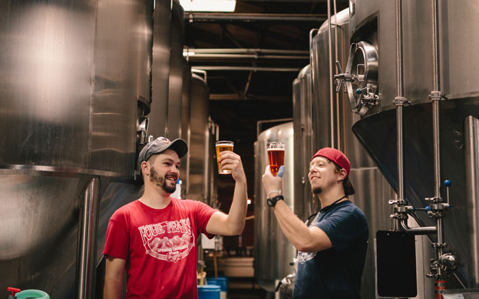 two men holding glasses of drinks in their hands
