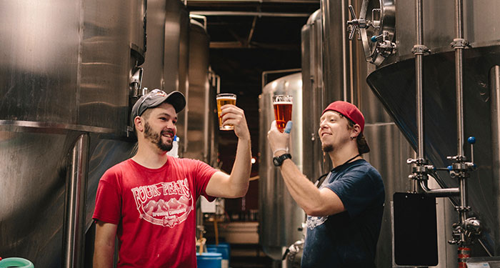 Persons holding beer and smiling