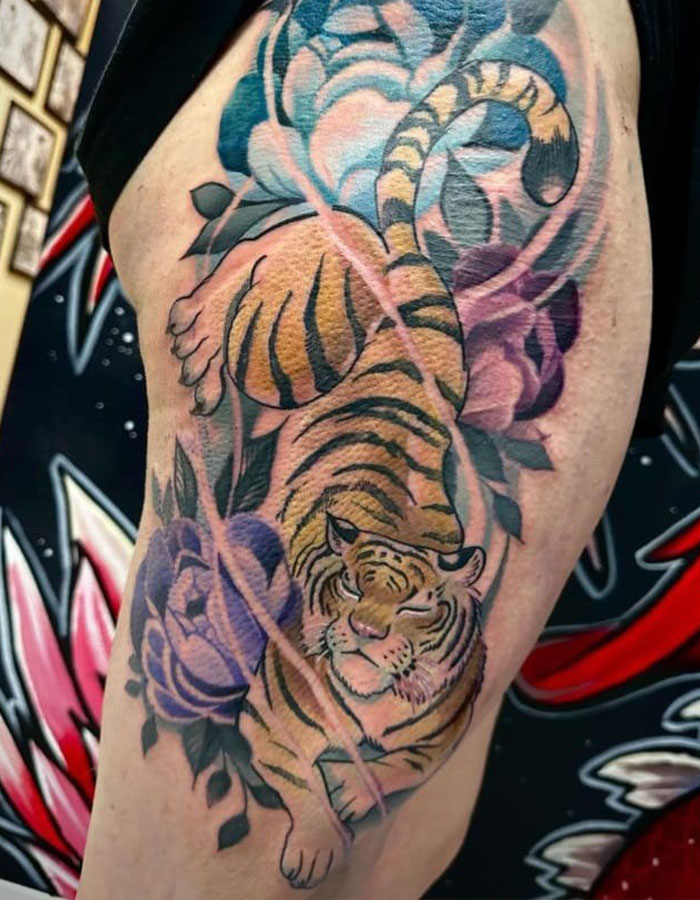 Tiger tattoo with purple flowers on thigh, showing one of many epic tattoo fails shared by folks online