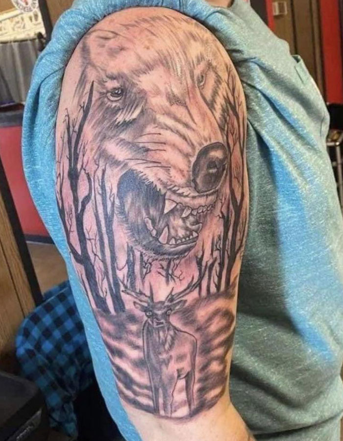 Tattoo fail showing a distorted wolf and deer design on upper arm with awkward anatomy and shading errors.
