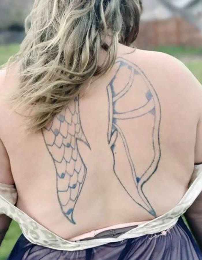 Back view of person with poorly designed tattoo wings on their upper back, showcasing an epic tattoo fail.