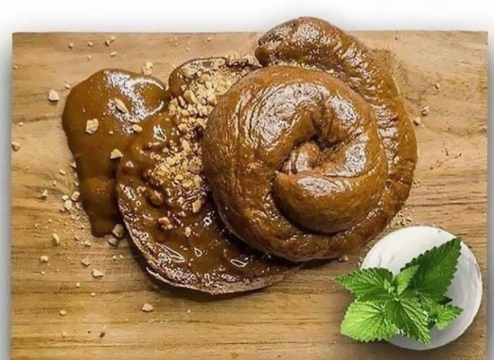 Unappetizing food resembling chocolate swirl on a wooden board with mint garnish.