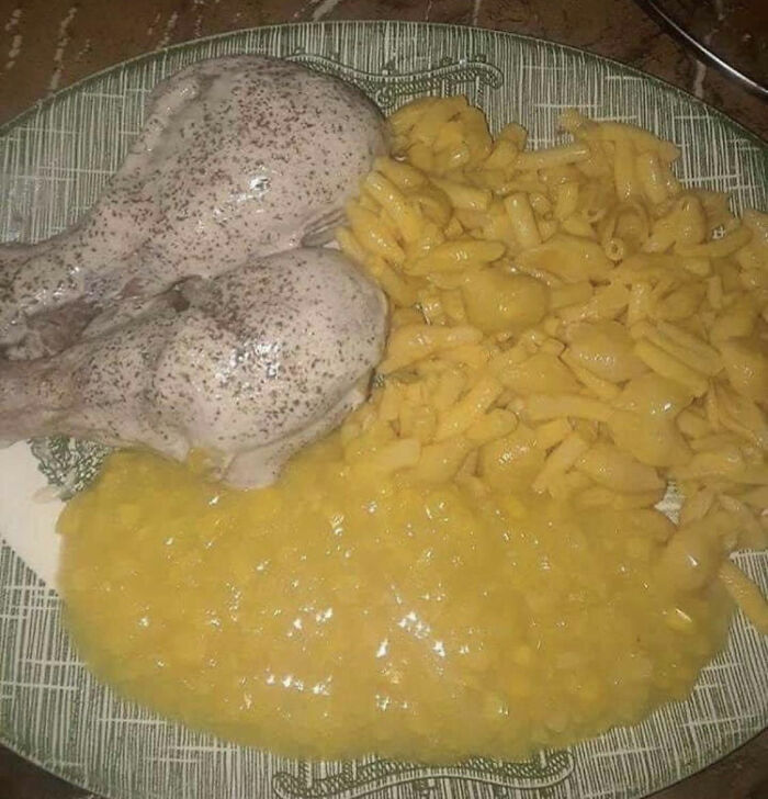 Unappetizing food picture featuring two pale chicken legs, mushy mac and cheese, and a yellow sauce on a plate.