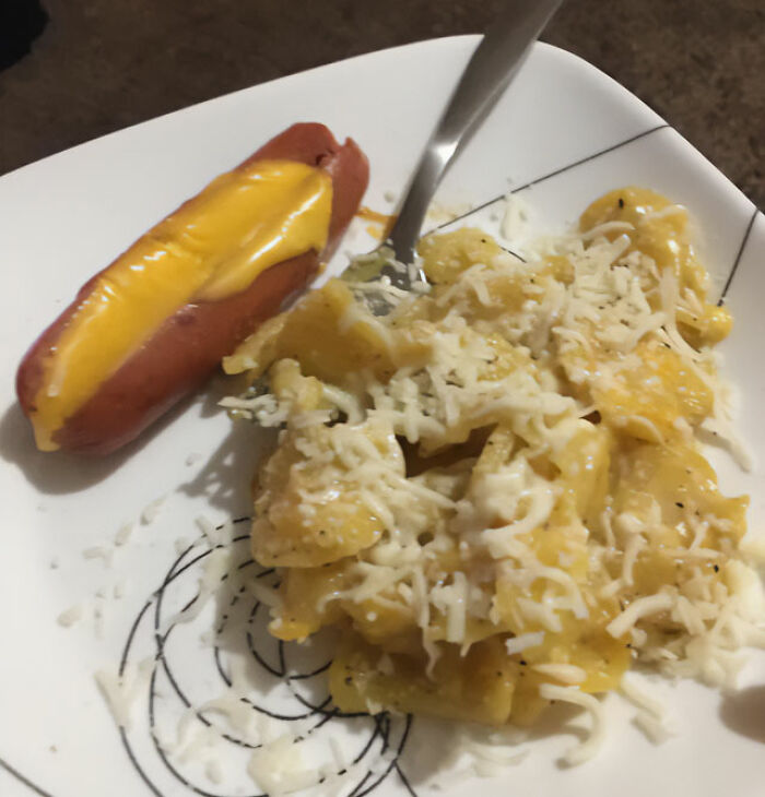 Unappetizing food: a plate with a cheese-stuffed hot dog and pasta topped with melted cheese.