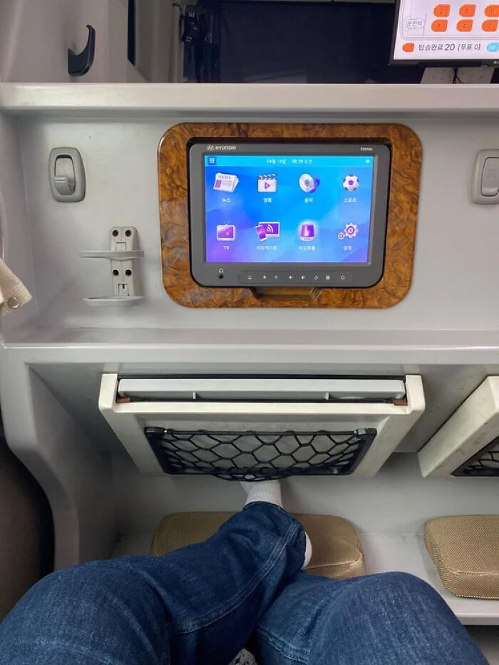 Person sitting in the train with a tv and lots of leg room 