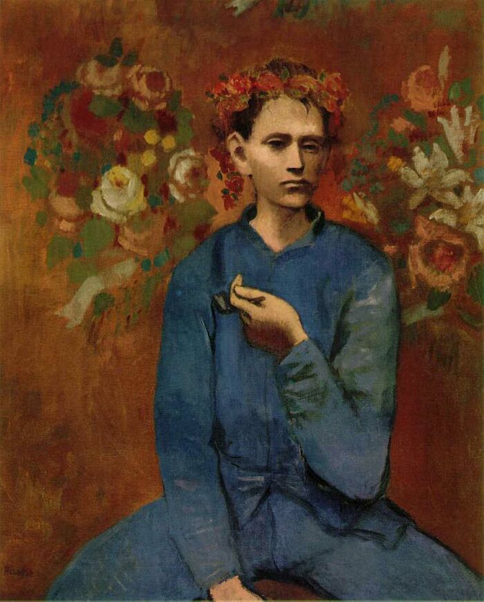 Boy With A Pipe by Pablo Picasso, 1905, oil painting depicts a Parisian adolescent boy who holds a pipe in his left hand and wears a garland of flowers on his head