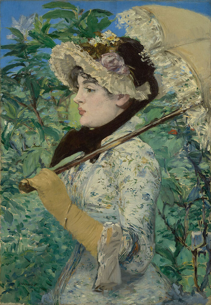 Spring by Édouard Manet, 1881, oil painting features young woman in a day dress with floral accents holds a parasol against a background of foliage