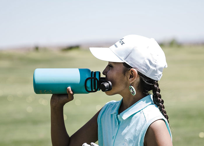 Woman drinking from blue water bottle