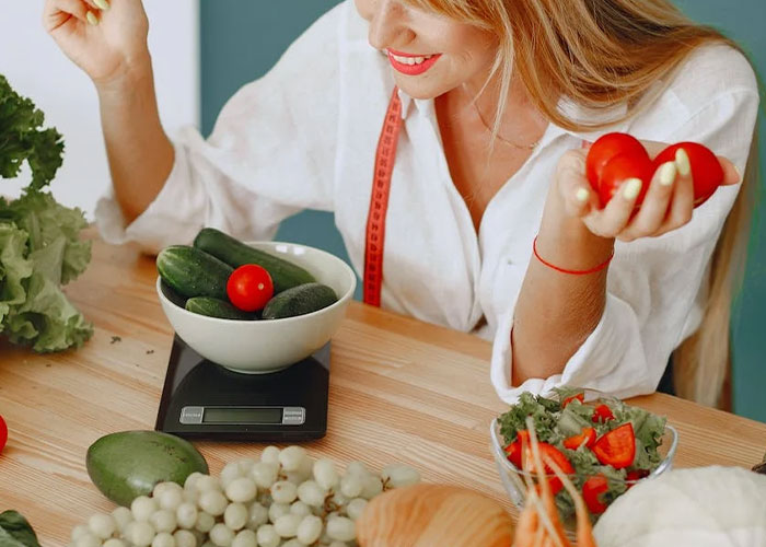 A woman weighs vegetables on a scale