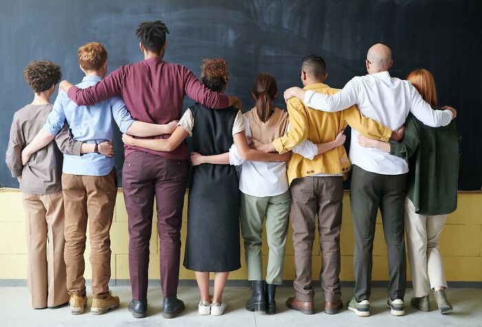 People with arms around each other, standing in front of a blackboard, embodying experiences worth having.