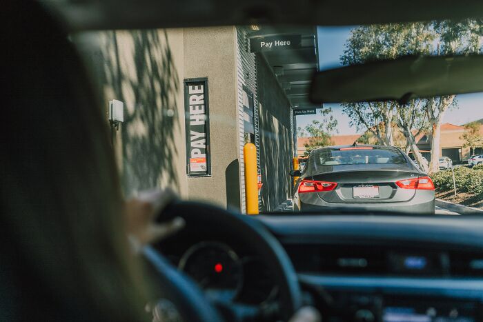 Woman sitting in her car in a drive thru 