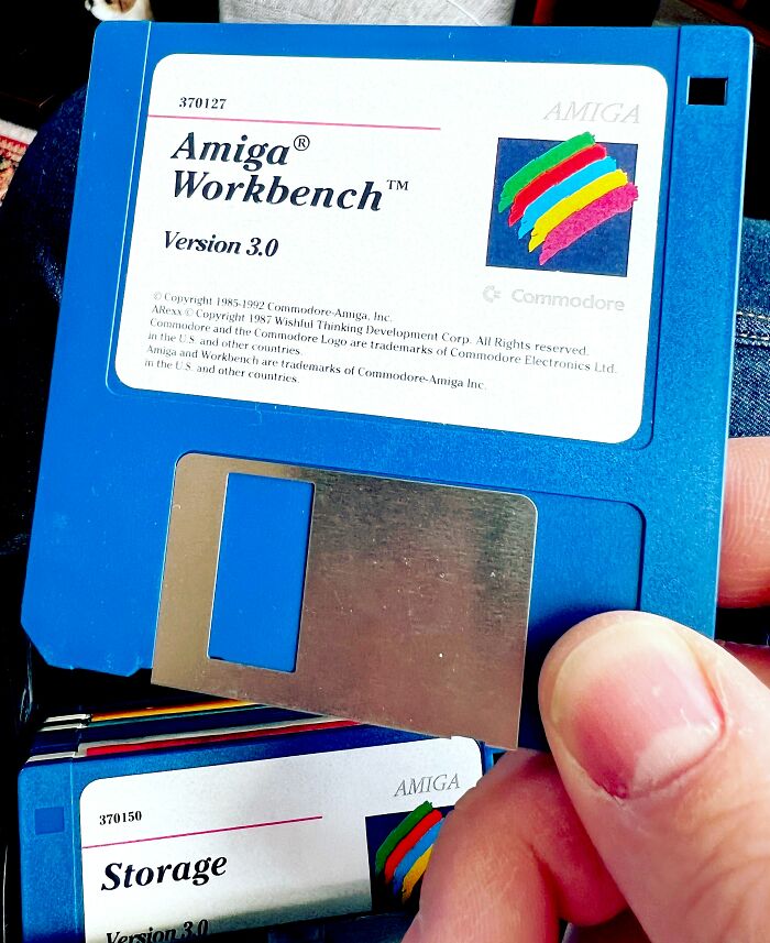 Person holding a blue floppy disk, showcasing one of the old gadgets that were trendsetters of their time.