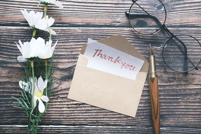 Envelope with "Thank you" note, surrounded by daisies and a pen, highlighting experiences worth having.