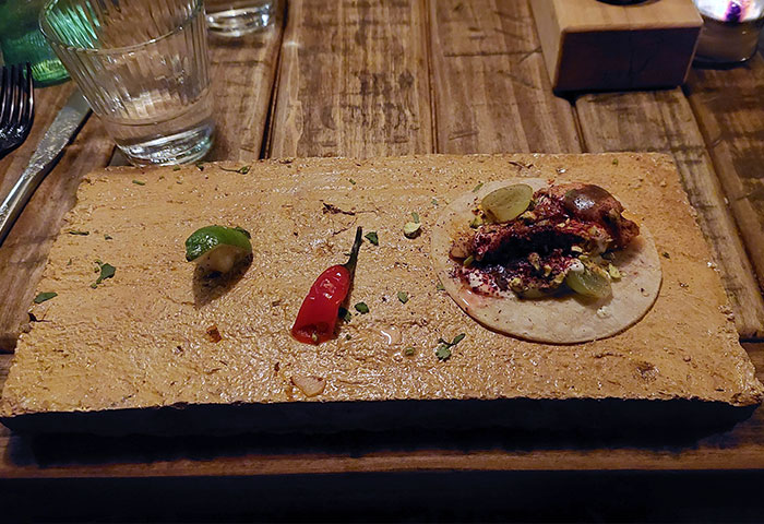 A Single Taco Served On A Brick Tile