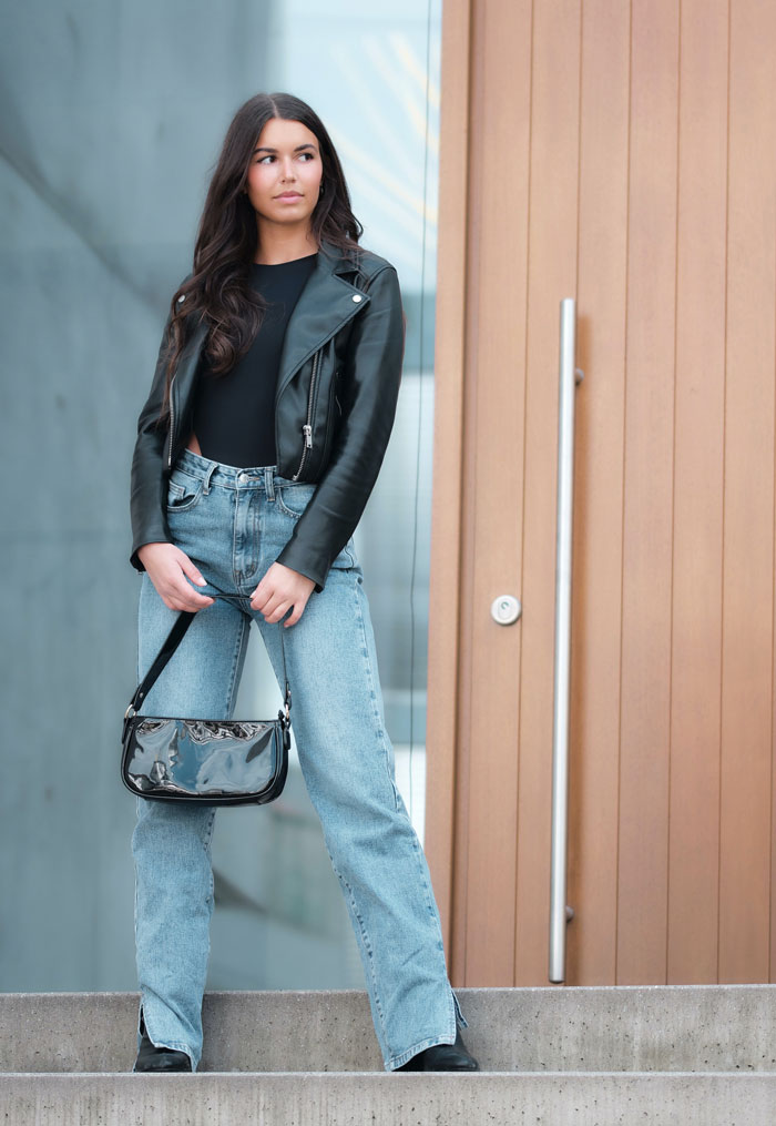Woman standing and wearing black shirt and blue jeans