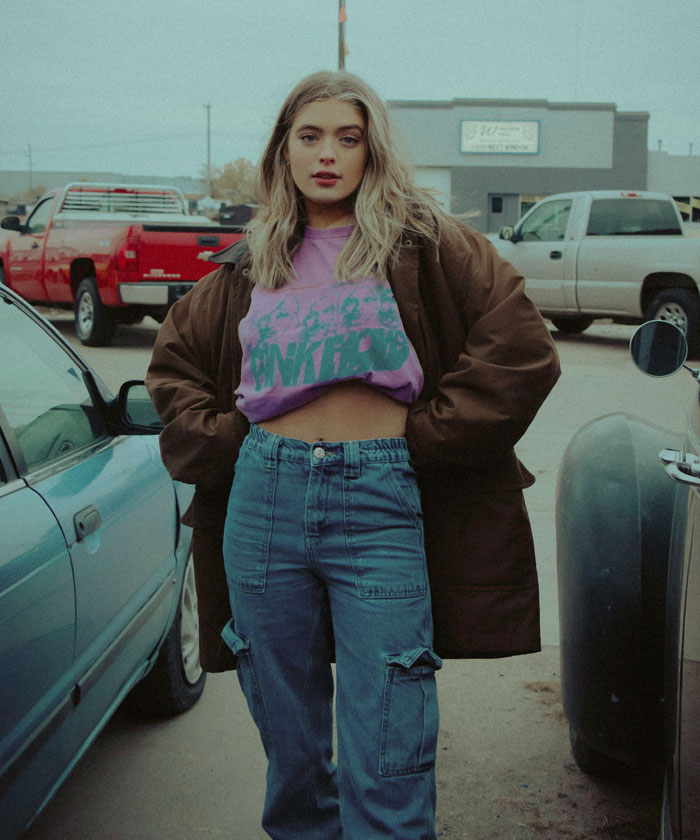 Woman standing and wearing purple shirt with blue jeans