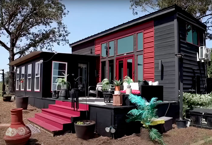 Black and red small tiny house design with outdoor seating and plants, showcasing modern compact living inspiration.