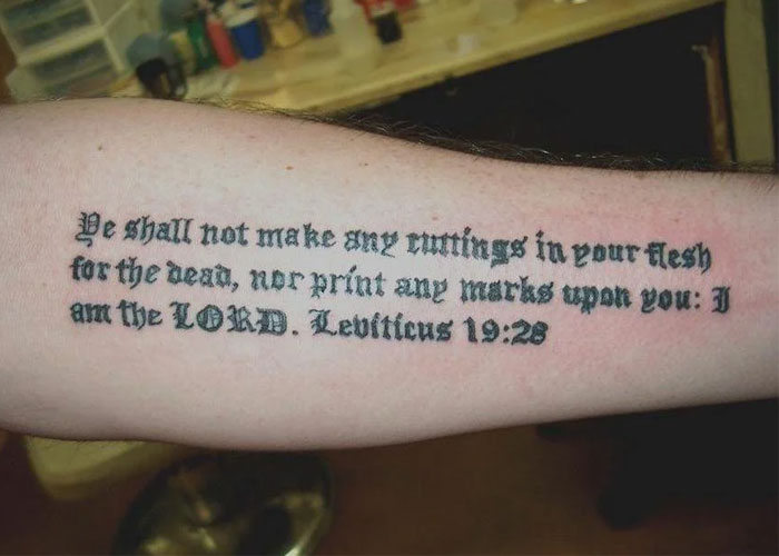 Arm with a tattoo design featuring a biblical quote, illustrating a lack of creativity according to some online users.