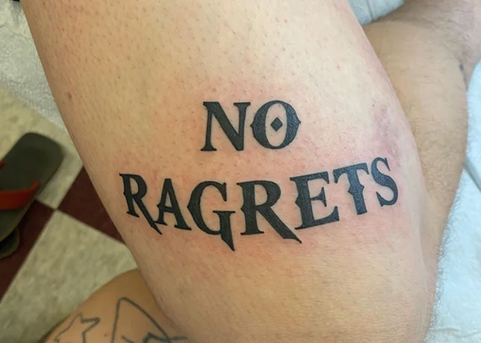 Tattoo design reading "NO RAGRETS" on skin, highlighting lack of creativity in tattoo choices.
