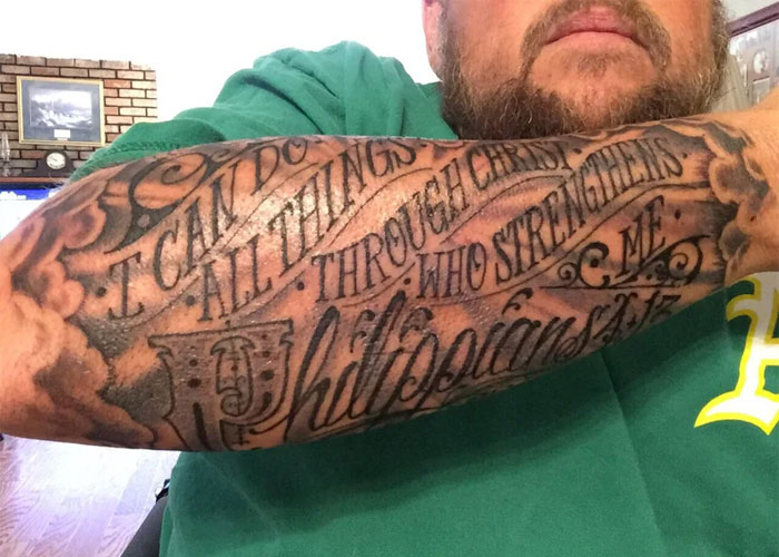Arm tattoo with text in bold font, featuring a Philippians 4:13 Bible verse.