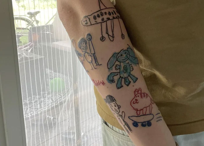 Creative tattoo designs with doodle-like drawings on a person's arm indoors.