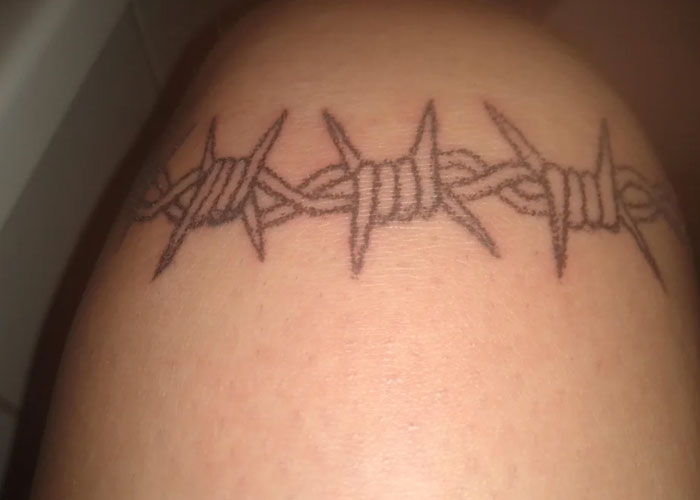 Barbed wire tattoo design, often labeled as lacking creativity, wraps around a person's arm.