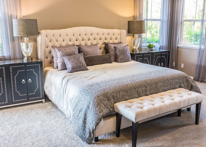 Modern bedroom with a tufted bed and bench, highlighting weird guest rules in someone’s house setting.