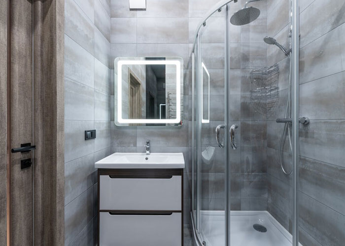 Modern bathroom with glass shower and illuminated mirror representing weirdest guest rules in house etiquette.