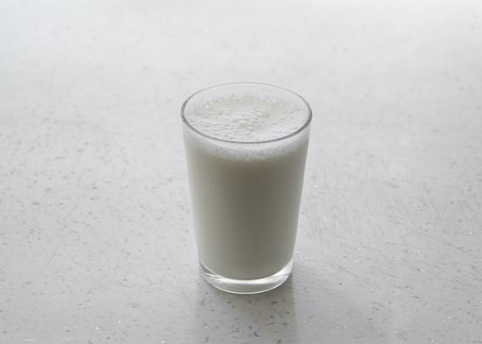 Glass of milk on a light surface, representing unusual guest rules involving drinks or food at someone’s house.