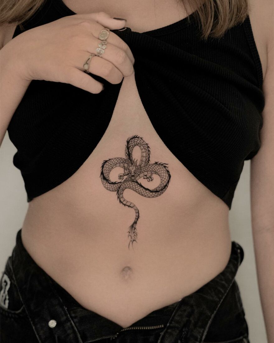 Dragon tattoo design on woman's torso, featuring intricate details and circular patterns on skin.