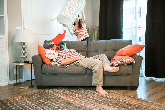 Man lying on couch while woman playfully holds a basket over him, illustrating worst trend that has ever existed.