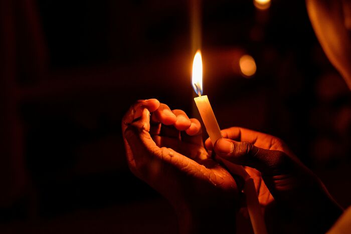 Hands holding a lit candle in the dark, symbolizing reflection on the worst trend that has ever existed topic.