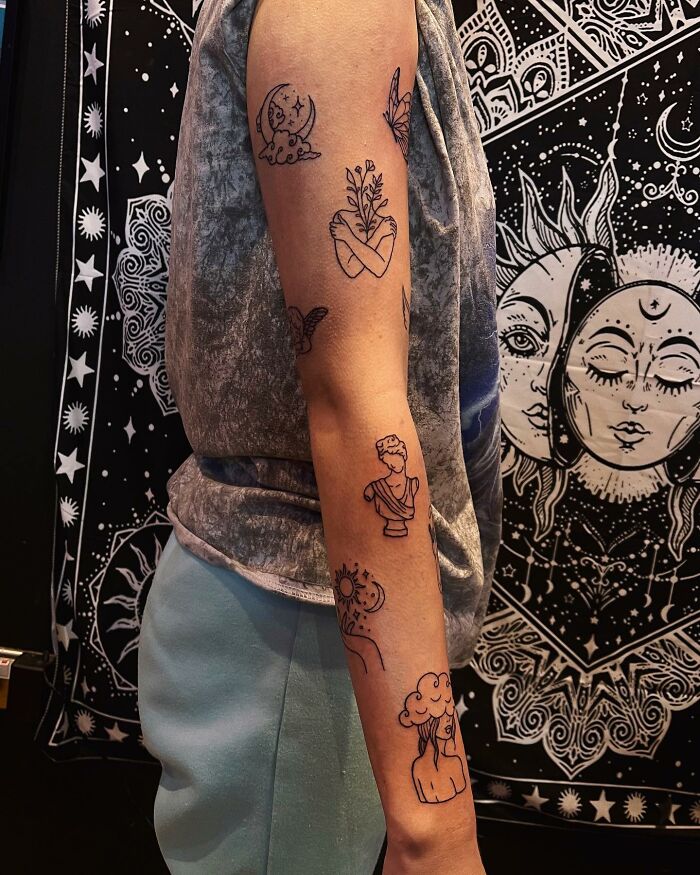 Arm featuring unique patchwork tattoos with celestial and nature themes, set against a tapestry background.