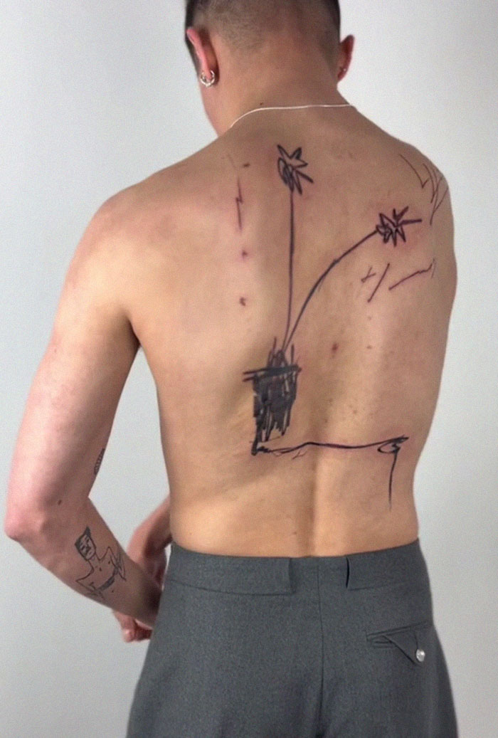 Viral tattoo with 2.5M views shows a man's back featuring a simplistic flower design, sparking mixed reactions.