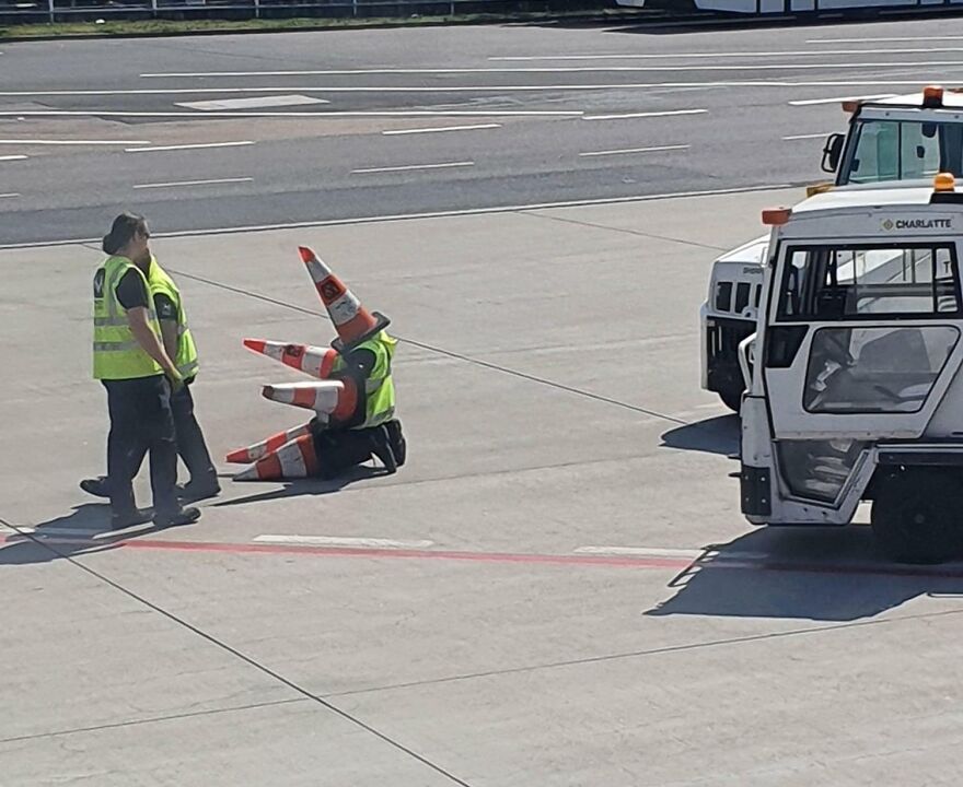 Airport worker with multiple traffic cones on her 