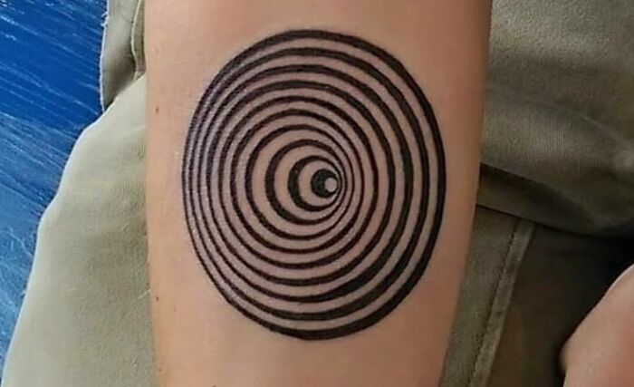 Optical illusion tattoo design with concentric circles, creating a mesmerizing visual effect on the forearm.