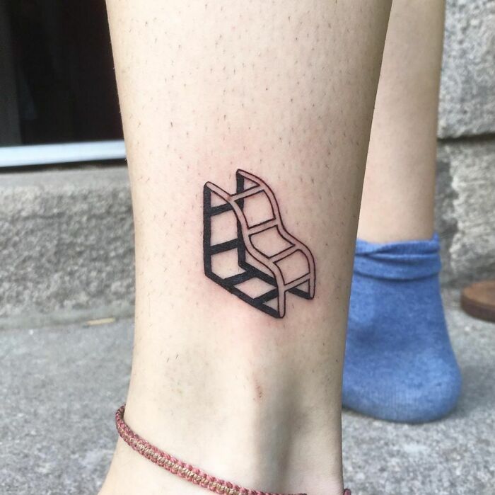 Optical illusion tattoo design on leg, featuring an impossible stair motif in black ink.