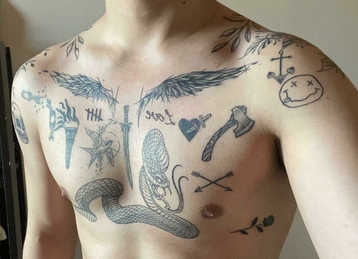 Chest adorned with various intricate patchwork tattoos, including wings, a snake, and a sword.