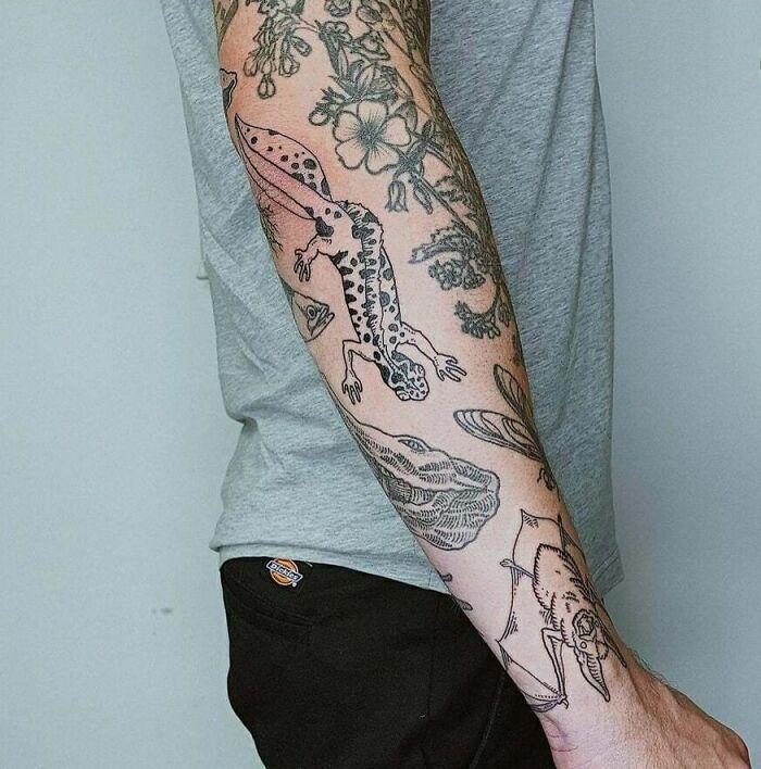 Colorful patchwork tattoo sleeve with floral and animal designs on a person's arm in a gray shirt.