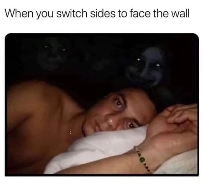 Man lying on pillow in dark room with eerie faces in background, illustrating funny and relatable introvert meme.