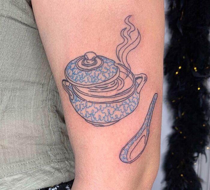 Watercolor tattoo of a steaming teapot on the arm, inspired by food tattoo ideas.