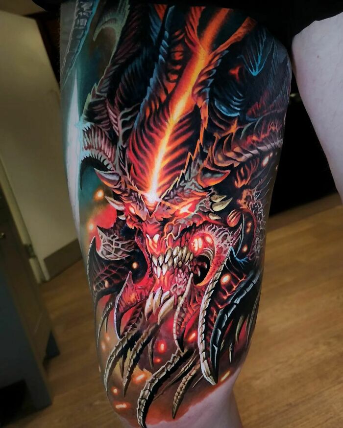 Detailed pop culture tattoo of a fiery demon with glowing eyes and sharp teeth on an arm.
